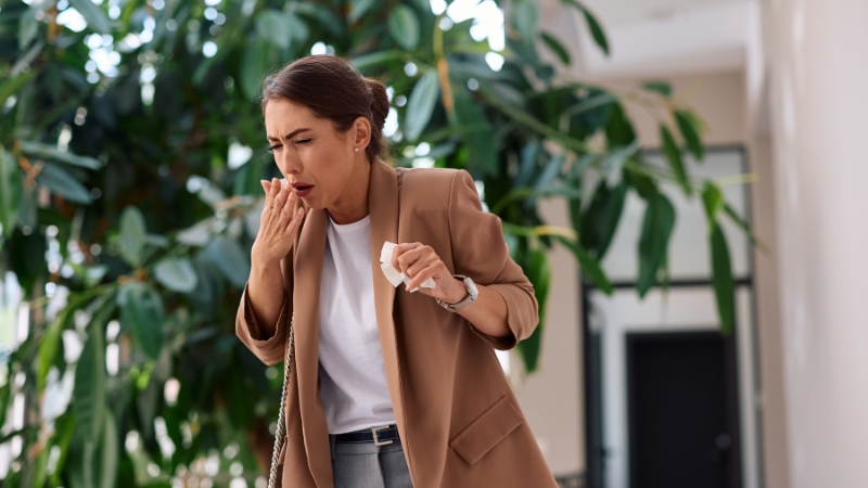 Žena kašlje i drži maramicu dok pokušava da ublaži napad kašlja