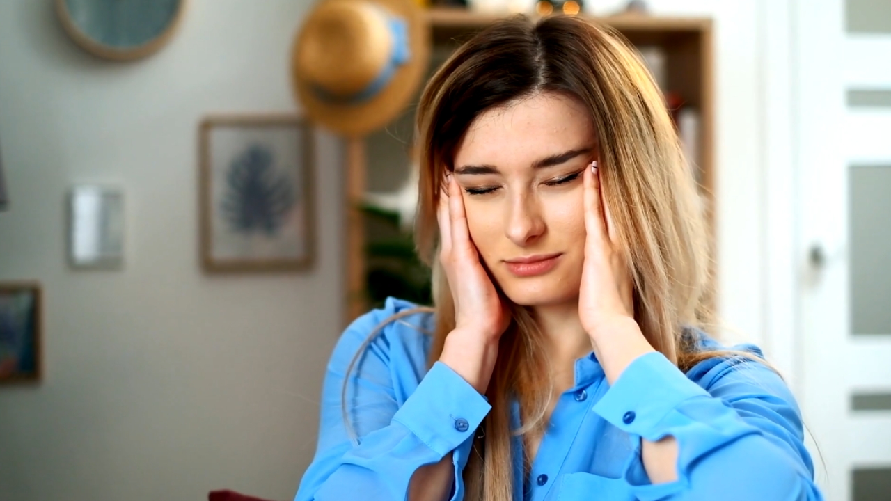 Umorna žena drži ruke na slepoočnicama i odmara oči