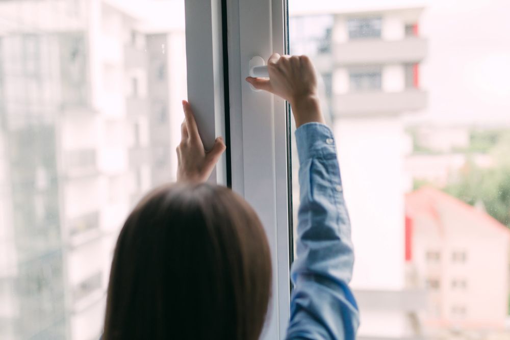 Žena otvara prozor kako bi provetrila stan i poboljšala kvalitet vazduha u prostoriji.